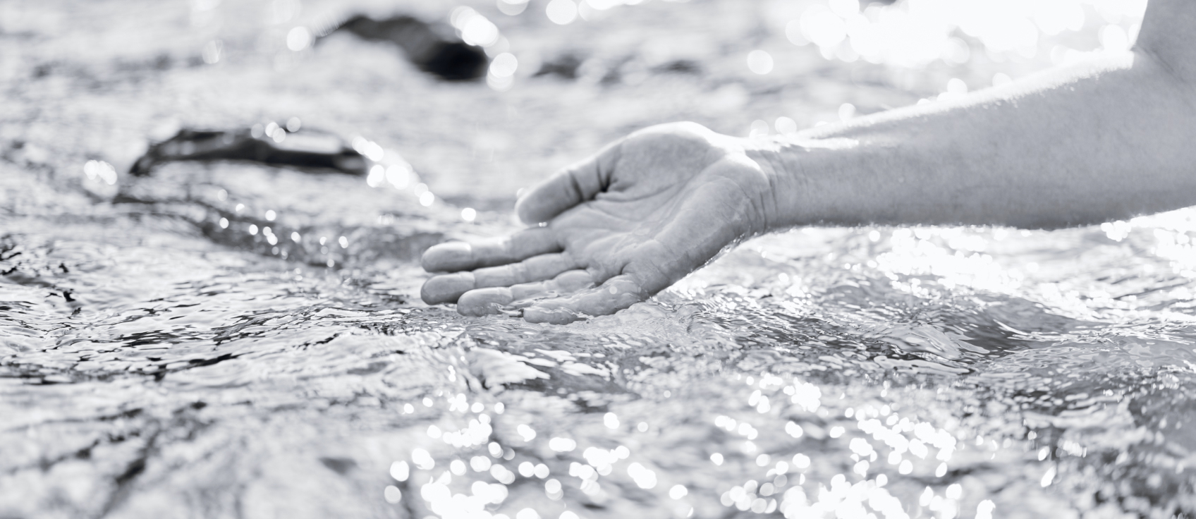 Hand, die sanft über das Wasser des Bodensees streicht